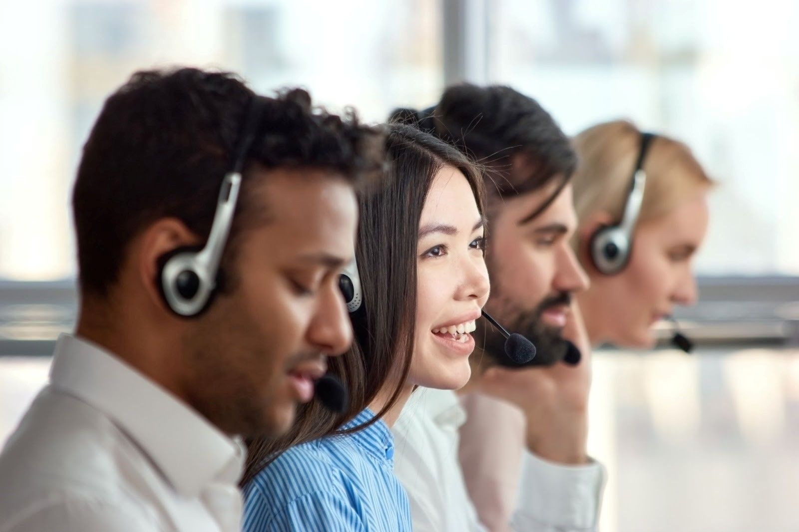four people wearing headsets in a call centre