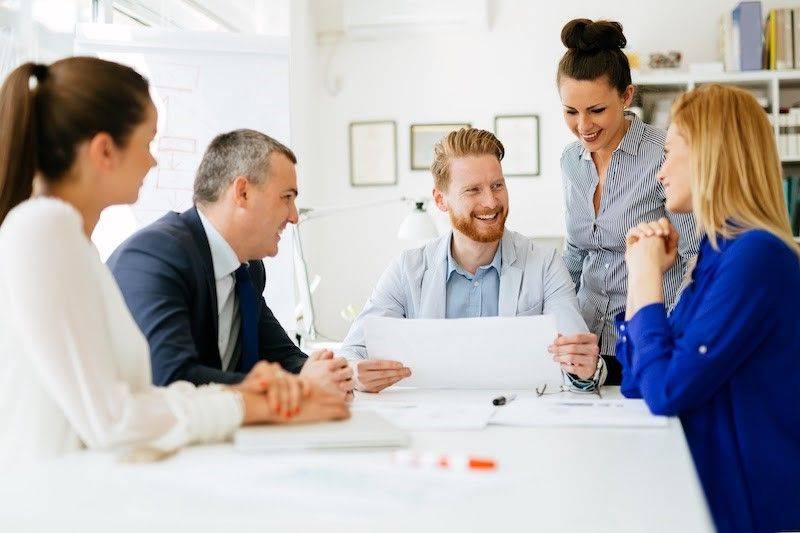 A team of people around a table in an office. 