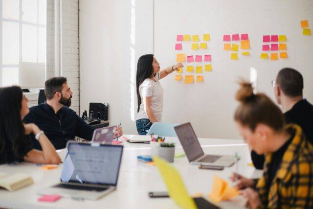Group sit in boardroom using post-it notes