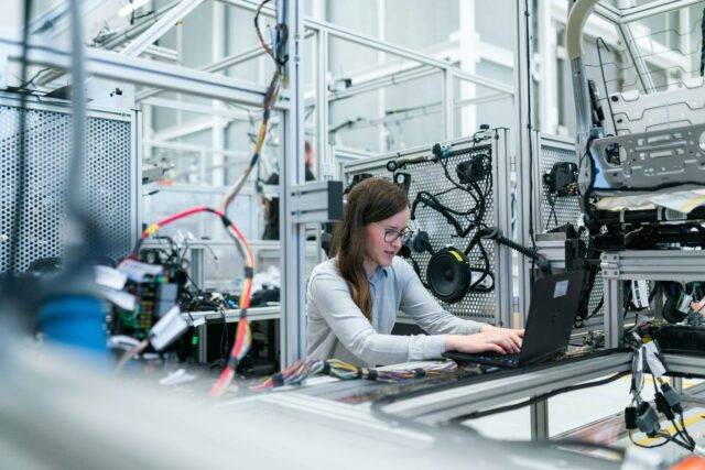 Woman sat at laptop surrounded by equipment