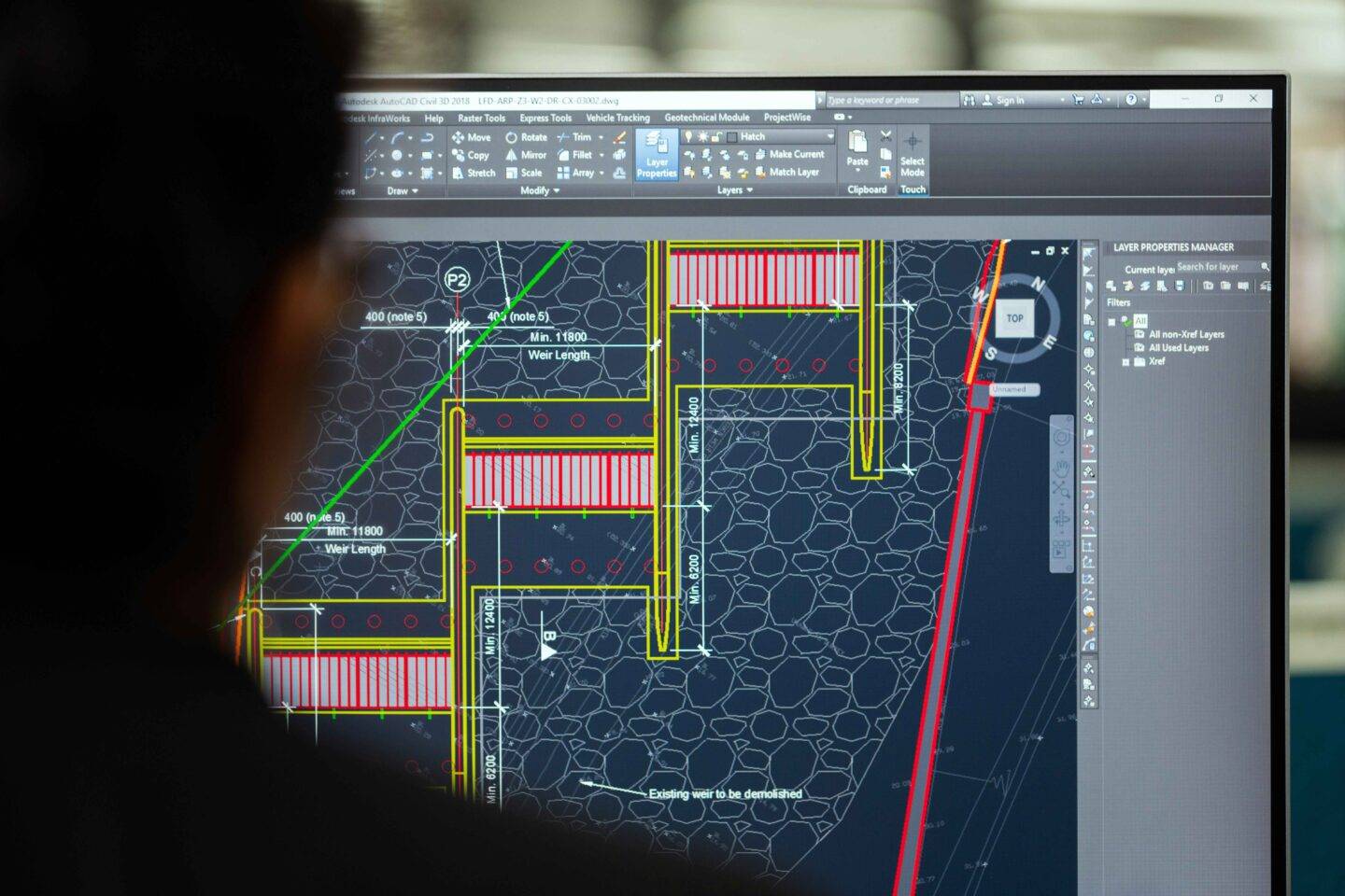 Person looking at a laptop screen with engineering drawings on it