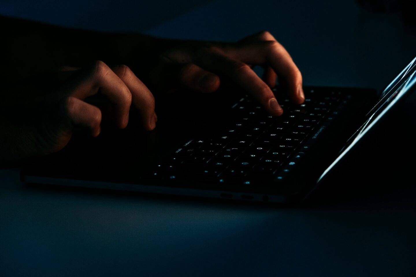 Someone typing on a laptop in a dark room