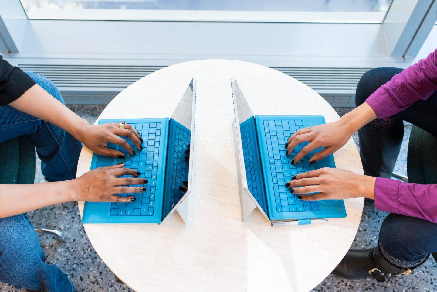 Two coworkers sat opposite on laptops