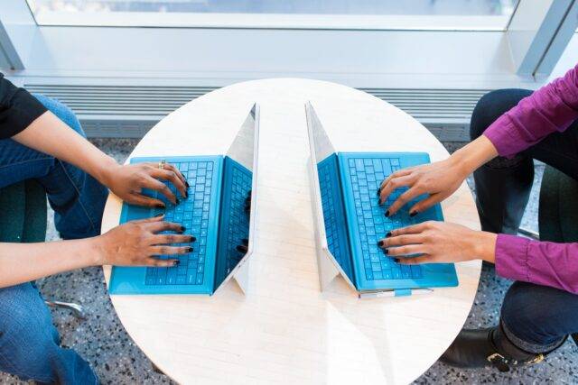 Two coworkers sat opposite on laptops